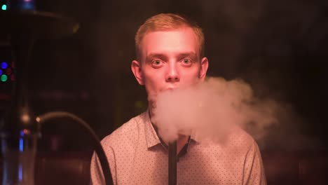 man smoking hookah in a nightclub