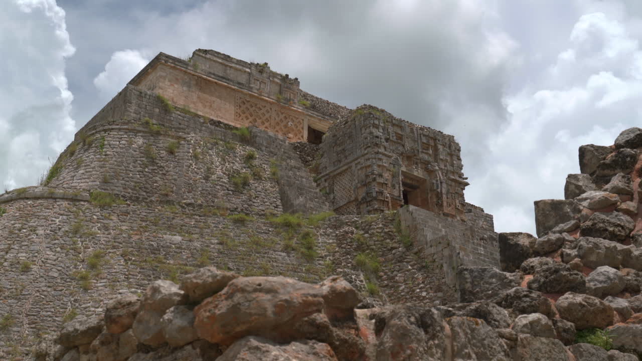 vista general de la pirámide del mago en uxmal, yucatán, rodeada de vegetación tropical, bajo ángulo de establecimiento mirando hacia arriba
