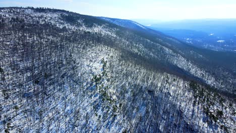 aerial drone video footage of a snowy mountain valley during early spring with sunny blue skies