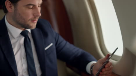 Confident-leader-using-tablet-on-airplane-trip.-Closeup-man-hands-touch-screen