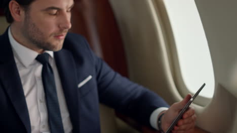 confident leader using tablet on airplane trip. closeup man hands touch screen