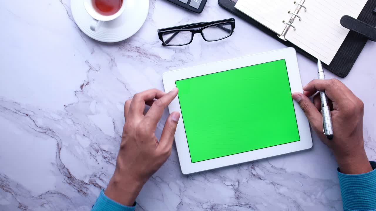 Person using a tablet with a green screen