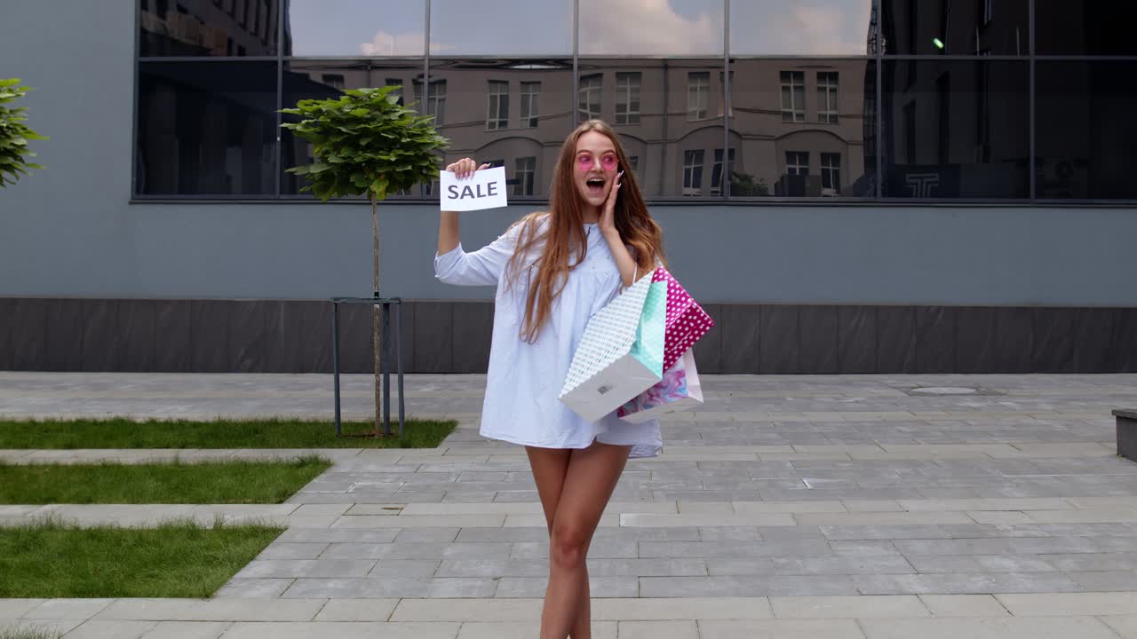 joven chica elegante mostrando texto de inscripción de palabra de venta, sonriendo, pareciendo satisfecha con los precios bajos