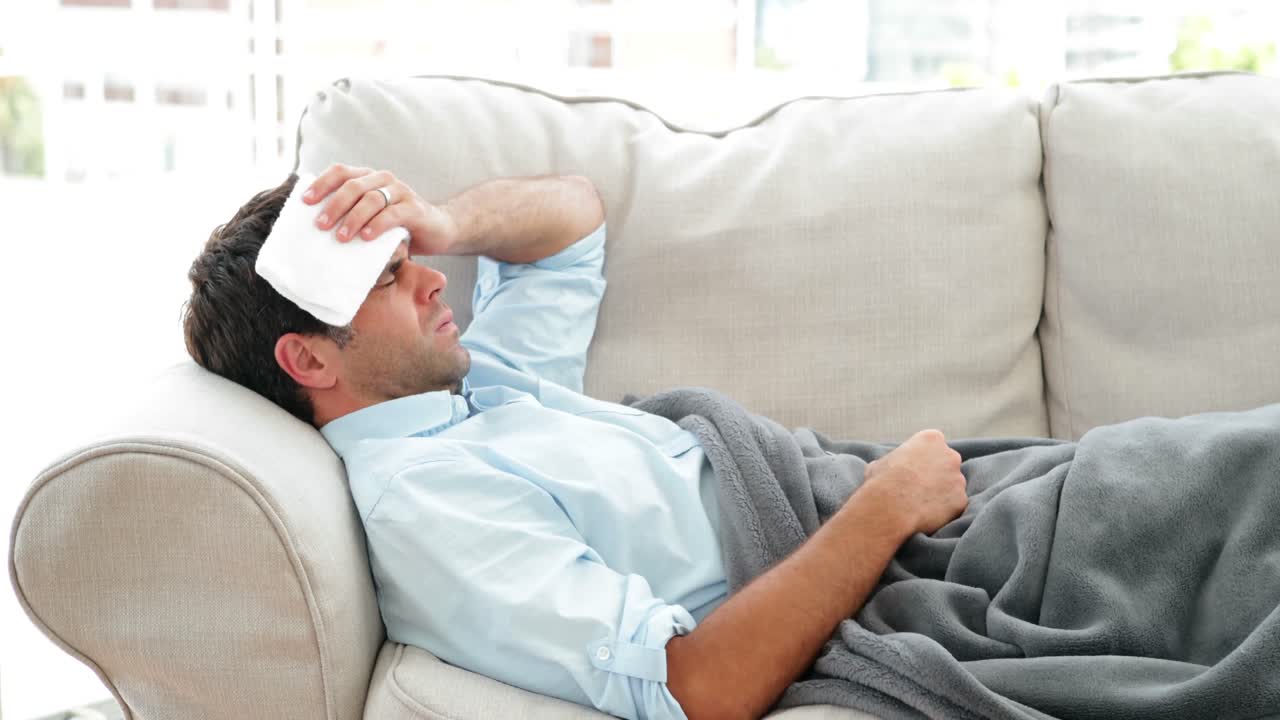 Man lying on the couch sick with a temperature