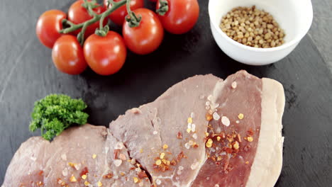 sirloin chop, cherry tomatoes and coriander seeds on chopping board