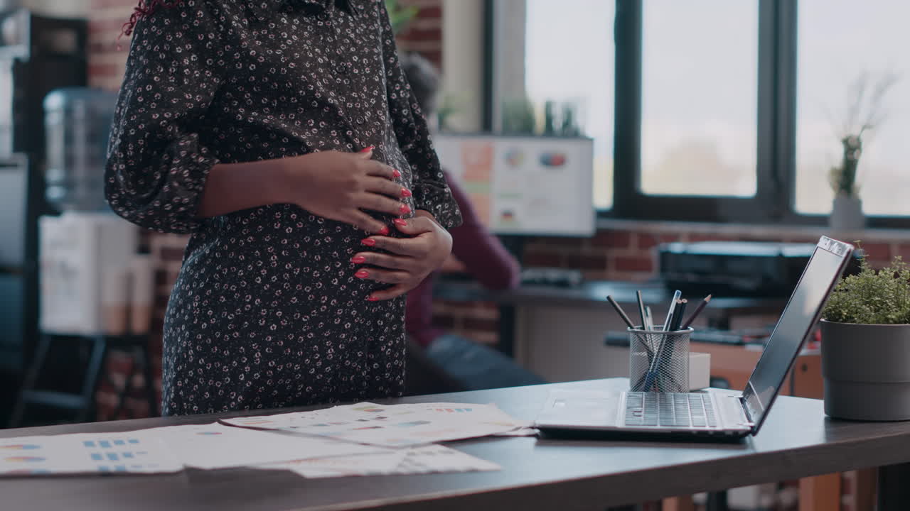 Close up of pregnant business woman holding hand on belly