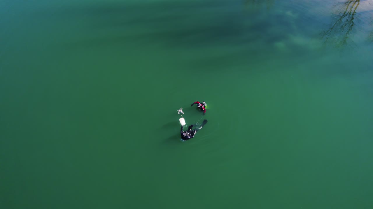 vista aérea de dos buzos nadando en aguas turbias en un lago en el sur de francia en pleno invierno