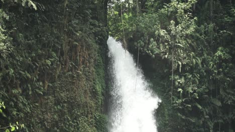 close up view of fast waterfall flow going down in indonesia, tilt down