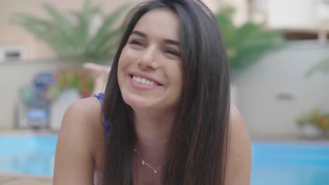 hermosa mujer morena tomando el sol junto a la piscina en un hotel de lujo
