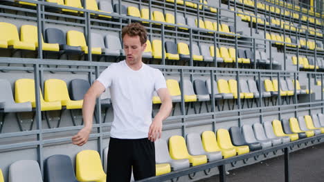 fitness joven atleta masculino haciendo ejercicios de estiramiento en el estadio