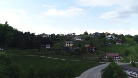 aerial drone footage captures picturesque houses nestled on lush green landscape, framed by stunning swiss countryside, against backdrop of bright sky, showcasing serene beauty of switzerland