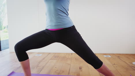 young woman doing yoga on wooden floored studio at home