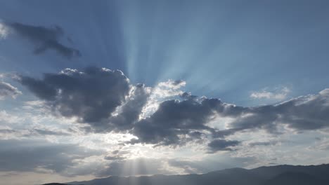 Vuelo-Al-Atardecer-Con-Drone-En-Un-Valle-Visualizando-Las-Montañas-Y-El-Cielo-Con-Nubes-Donde-Algunas-De-Ellas-Tapan-El-Sol-Y-Salen-Destellos-En-Forma-De-Rayos-Creando-Una-Luz-Impresionante