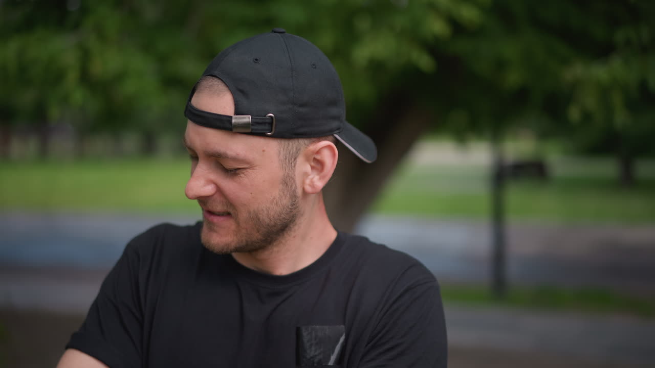 Gentle Warmup Before Exercise, Individual Loosening Muscles In Park, Man Performing Slow Mobility Stretches With Cap On Head, Man In Park Doing Gentle Stretching Exercises For Preparation