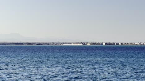 Vista-Lejana-De-Un-Avión-Aterrizando-En-El-Aeropuerto-De-Hurghada-Vista-Desde-El-Mar-Rojo-En-Egipto