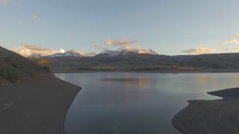 hermosa puesta de sol que establece un disparo que cae sobre la ladera de la montaña en las montañas rocosas cubiertas de nieve y el lago