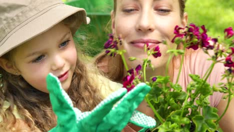 Cute-little-girl-looking-at-pot-of-flowers-with-her-mother