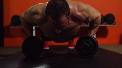 muscular man performing push-up exercise with dumbbell