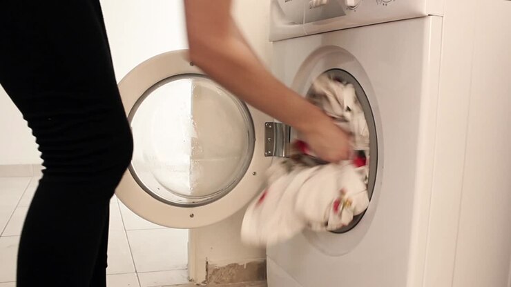 Person Loading Laundry into a Washing Machine