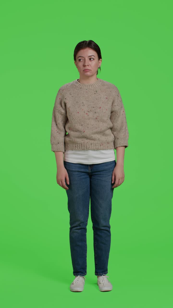 Vertikal video: Frontbillede af utilfreds kvinde, der står foran baggrund i fuld figur