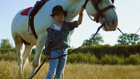 little boy is playing with his pet on a farm holding a horse by a leash