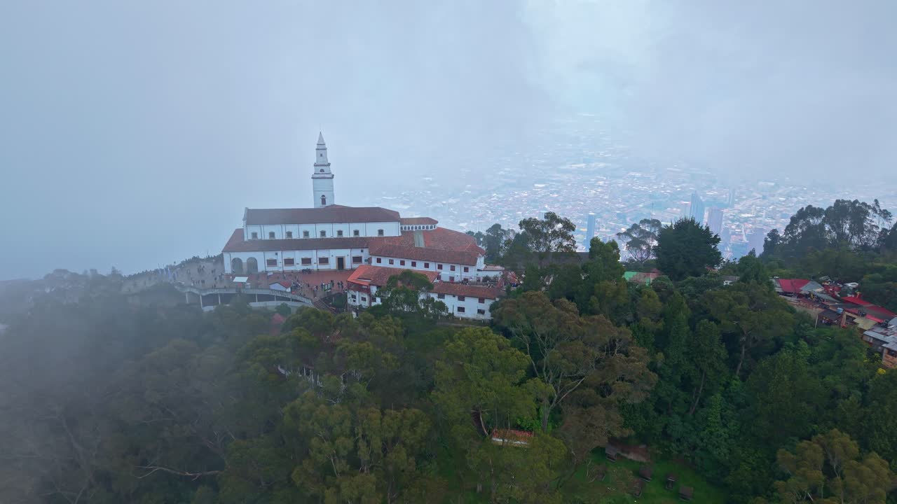 Backward drone flight reveals Monserrate emerging from swirling clouds, hiding Bogotá’s vast cityscape, the sanctuary floats in a mystical, dreamlike atmosphere that feels sacred, serene and cinematic