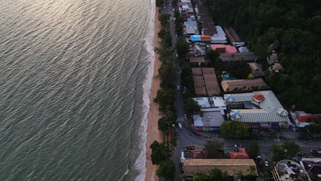 una toma de drones de una hermosa puesta de sol sobre el mar en calma con vistas a las casas en la playa blanca en una isla fascinante