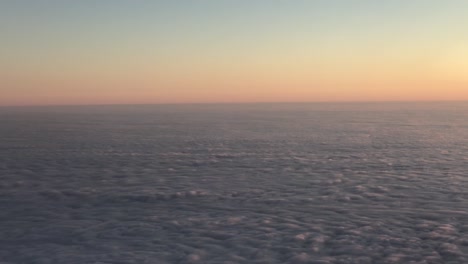 aerial shot above the clouds while on a plane during sunset