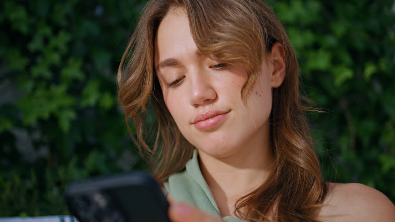 Portrait lady messaging cellphone at sunny green nature. Woman browsing phone