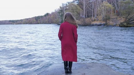 girl standing by a lake in a red coat