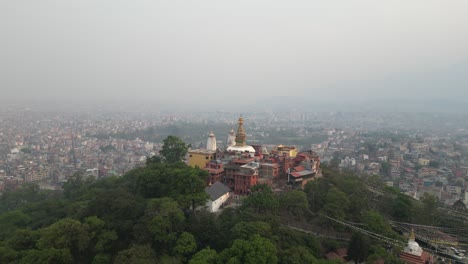 aerial drone shot zooming in on buddha temple on a hill in kathmandu, nepal at the base of the himalayas