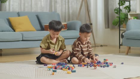 full body of asian kids assemble the construction set colorful plastic toy brick on a mat at home