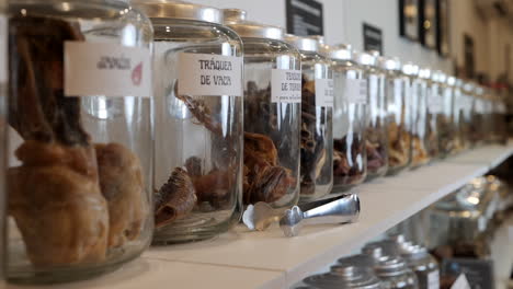 filas de frascos de vidrio anticuados llenos de golosinas secas para perros exhibidos con pinzas de servicio en la tienda de mascotas