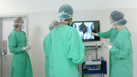 diverse surgeons wearing surgical gowns looking at x-ray scans in operating theatre, slow motion