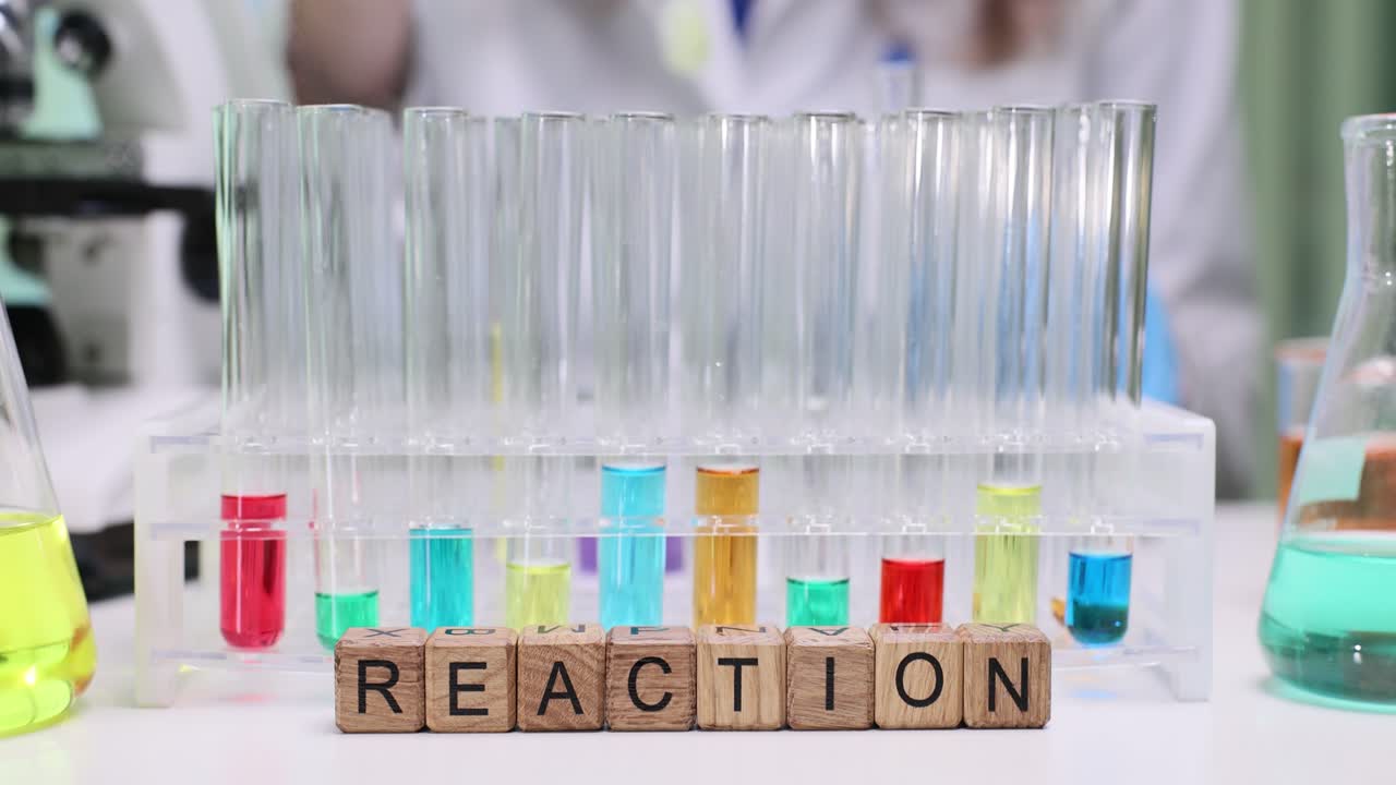 Wooden blocks spell reaction near rack of colorful test tubes