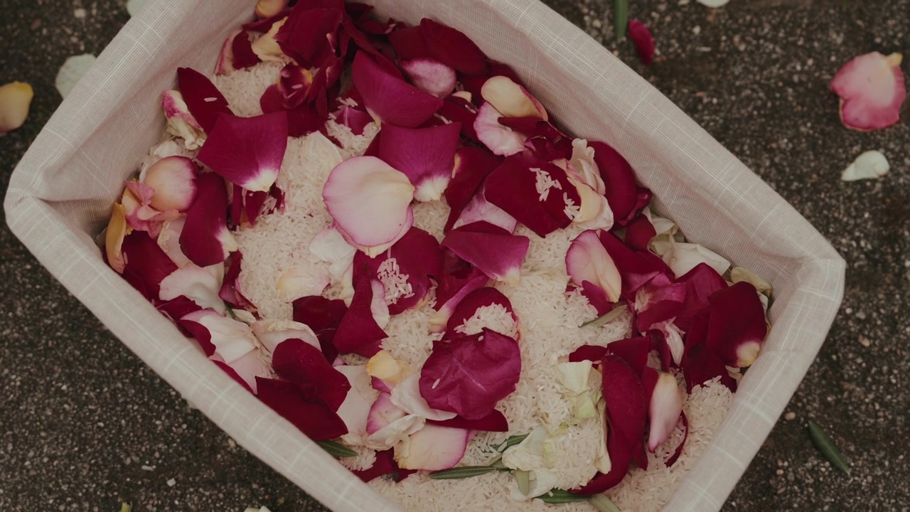Cesto di stoffa riempito di petali di rosa rossi e rosa a terra