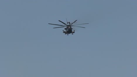 military cargo helicopter flies through blue skies