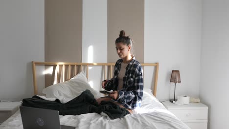 mujer sentada en la cama usando el teléfono
