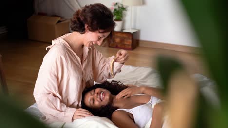 happy young lesbian couple with pizza lying on blanket