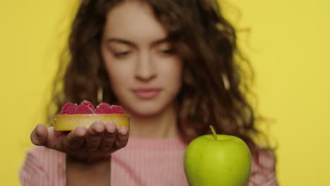 mujer joven eligiendo manzana en lugar de pastel para la nutrición de la dieta en el estudio