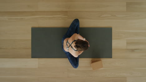 vista superior de una mujer de yoga practicando una pose de loto hacia adelante en un estudio de ejercicios disfrutando de un estilo de vida saludable, practicando meditación en una colchoneta de ejercicios.
