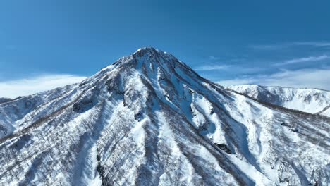 Aerial-wide-shot-orbiting-mountain-Japan-mount-myōkō,-on-a-clear-winter-day,-a-volcanic-mountain-in-Myoko-Togakushi-Renzan-National-Park-region