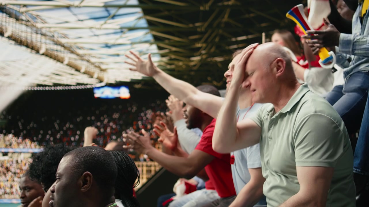Tifoso di calcio frustrato che guarda un momento di tensione della partita dagli spalti dello stadio.