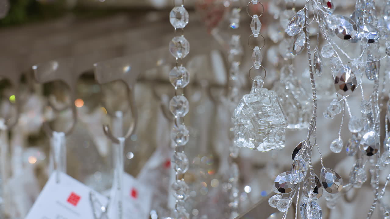 Close up hand view of person touching sparkling crystal decoration in decor shop, showcasing festive ornaments in well-decorated interior of store