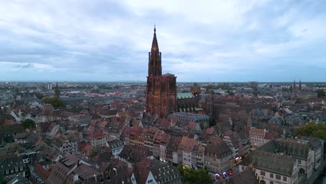twilight aerial view of strasbourg with the illuminated strasbourg cathedral towering over the charming rooftops of the historic city center, under a peaceful blue sky