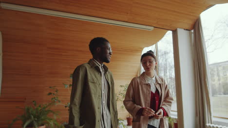 multiethnic man and woman walking in auditorium and speaking