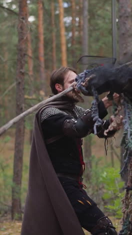 el caballero cae después de la huelga del monstruo en el bosque de coníferas en cámara lenta. soldado de mediana edad pierde en la batalla con el demonio en la reconstrucción. juegos tolkienistas