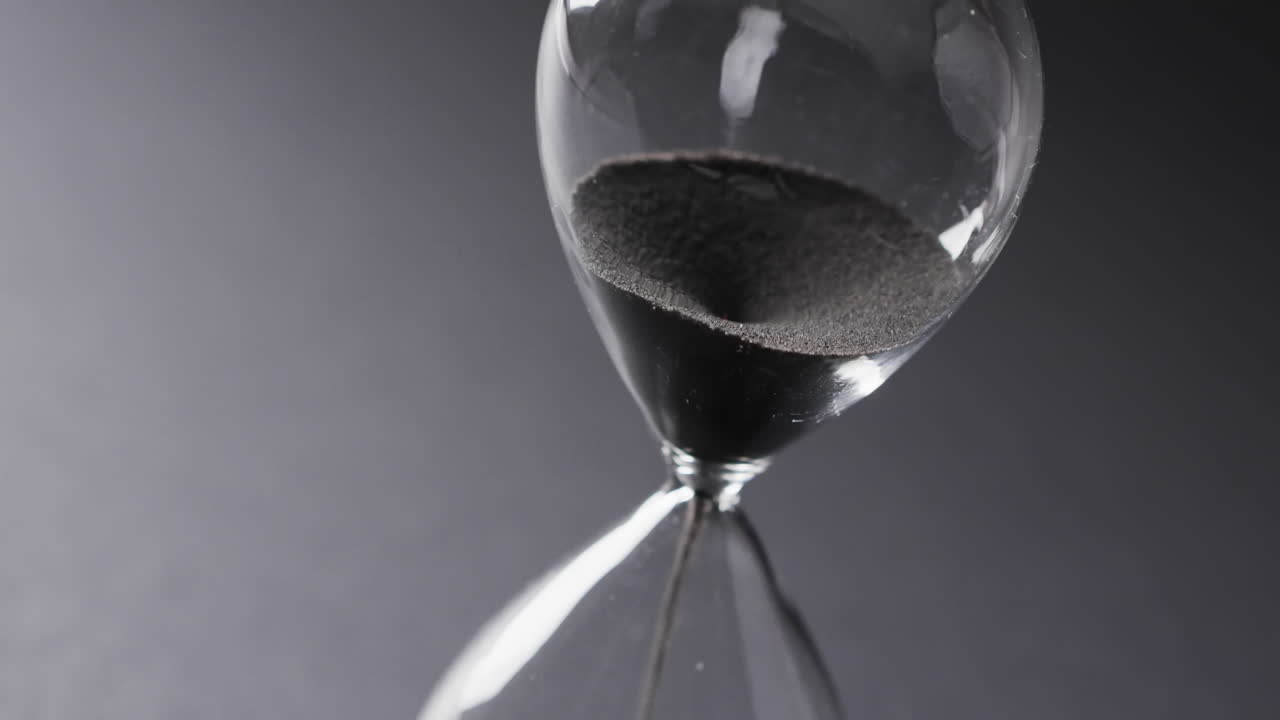 Video of hourglass with sand pouring, copy space on grey background