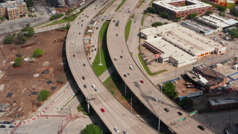 Forwards-tilt-up-reveal-of-multi-lane-highway-heading-to-interchange.-Aerial-view-of-busy-main-road-leading-through-town.-Dallas,-Texas,-US