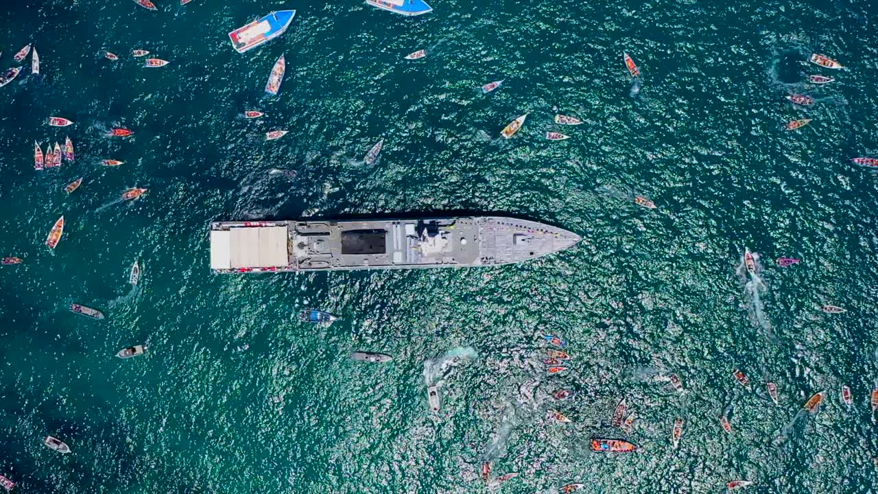 Boats gather on sea for faith procession, aerial view, calm vibe